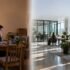 home office into a modern, collaborative coworking space with glass meeting rooms, desks, plants, and office furniture.